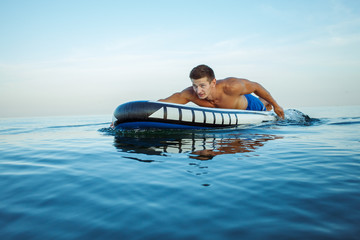 Man doing paddle surf at sunrise