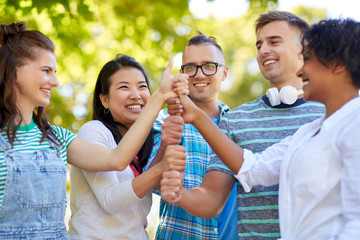success, friendship and international concept - group of happy smiling friends making high five in park