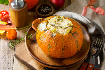 Thanksgiving Turkey dinner. Baked pumpkin stuffed with Turkey, rice and vegetables on rustic background. The concept of food on thanksgiving. Copy space.