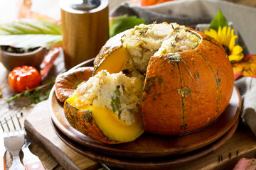 Thanksgiving Turkey dinner. Baked pumpkin stuffed with Turkey, rice and vegetables on rustic background. The concept of food on thanksgiving.