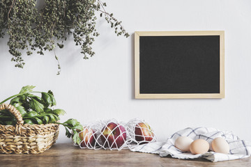 Stylish interior design of kitchen space with small table with mock up frame, herbs, apples and...