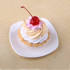Tasty Homemade cupcake, muffin with cream and cherry. Close up view delicious sweet dessert isolated on white.