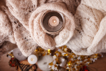 Lit Candle White Knitted Sweater on Plank Wood Table by Window. Cozy Winter Autumn Evening. Natural Light Authentic Tranquil Atmosphere. Kinfolk Hygge Slow Living Style. Top view