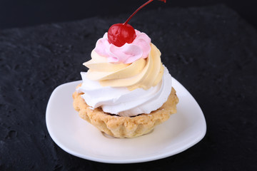 Tasty Homemade cupcake, muffin with cream and cherry. Close up view delicious sweet dessert isolated on white.