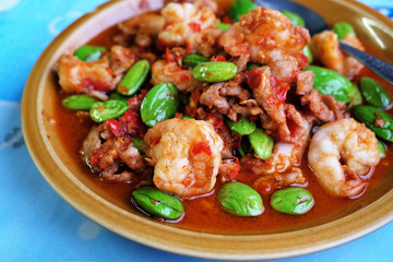Stir-Fried Twisted Cluster Bean with Shrimps/Bitter Bean and Crispy Pork on a White Dish Over Blue Table