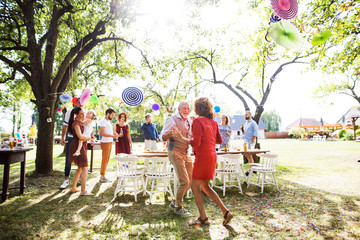 A senior couple dancing on a garden party outside in the backyard.