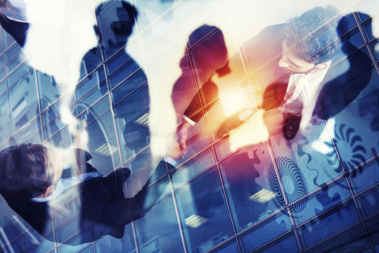 Handshaking business person in office. concept of teamwork and partnership. double exposure with gears system and network effects