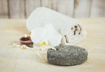 Oval pumice stone with natural sting, candle burning, rolled towel and white orchid blossom on the...