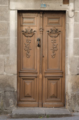 Puerta de madera pintada de ocre en pared de sillería de piedra granítica.
