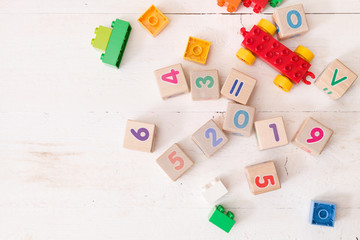 Top view on wooden cubes with numbers 2019 and multi-color toy bricks on old white wooden background. Toys in the table. Early learning and development.