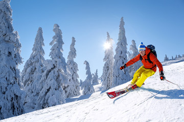 Skier skiing downhill in high mountains against blue sky - obrazy, fototapety, plakaty