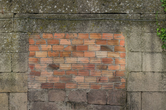 Puerta tapiada con ladrillos en muro de piedra