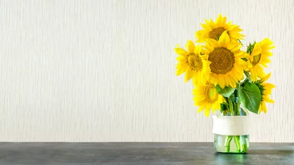 Rolgordijnen Bright yellow big sunflowers in glass vase on dark table on light texture background. Mockup banner with sunflower bouquet with copy space. © irissca