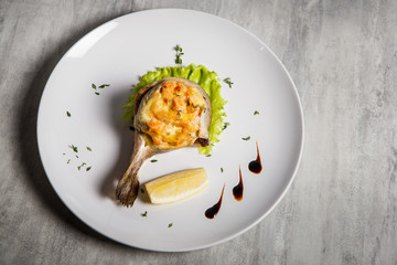 top view on baked trout with stuffing, salad, lemon and sauce