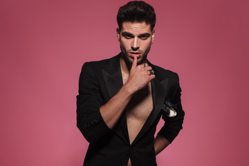 seductive man in black tuxedo touching his lips