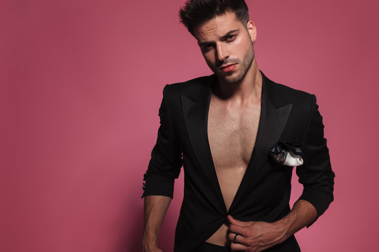 portrait of sexy man with bare chest buttoning his tux