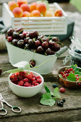 Mix of fresh berries and fruit in vintage wooden box on rustic wooden background. Raw healthy food. Assorted summer berries and fruit.