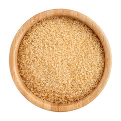 Brown refined sugar in wooden bowl isolated on white. Top view.
