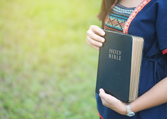 A woman is holding and hug the bible in the morning. Hands folded in prayer on a Holy Bible in life...