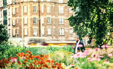 Fototapeta na wymiar Hipster businessman with smartphone walking in park in London.