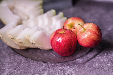 Apples and melon on a platter. Apples with water drops.