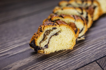 Roll with poppy seeds sliced lying on the table. Bread products.