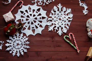 New Year's concept. Snowflakes cut from paper, gifts, scissors on a wooden table