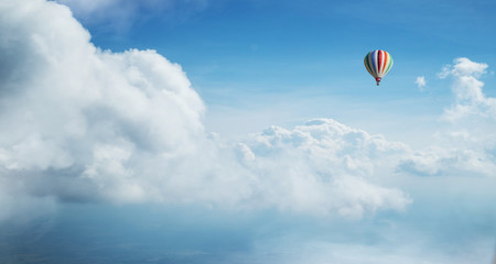 Kolorowy gorące powietrze balon latający przeciw błękitnemu chmurnemu niebu. - 222938897