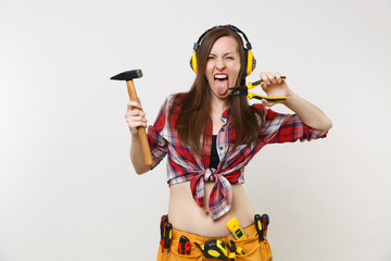 Strong fun young handyman woman in plaid top shirt, denim shorts, noise insulated headphones, kit...