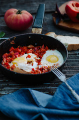 Shakshuka, Fried Eggs with Tomato Sauce in a Pan, Rustic Style and Wooden Background