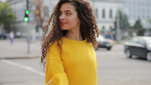 Happy smiling cute curly teen girl in city wear orange clothes