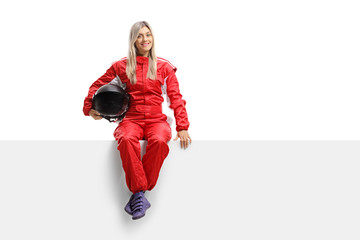 Female racer in a suit sitting on a panel - obrazy, fototapety, plakaty