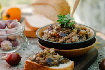 Traditional Caucasian saute from stewed eggplants, peppers, onions, tomatoes and herbs on the old background in rustic style