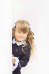 Little cheerful blue-eyed girl first-class with winded hair with bantikami and glasses in school uniform with a briefcase on September 1 is at the school on a white background