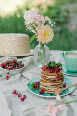 Stack of banana pancakes on a blue plate with fresh berries and honey for breakfast