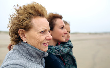 Fototapeta premium Closeup of three generations female looking at sea on the beach in autumn