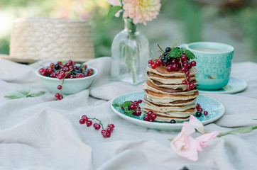 Stack of banana pancakes on a blue plate with fresh berries and honey for breakfast