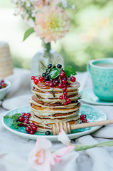 Stack of banana pancakes on a blue plate with fresh berries and honey for breakfast