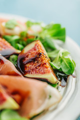 Tasty appetizing autumn salad with jamon, balsamico and figs served on plate. Closeup