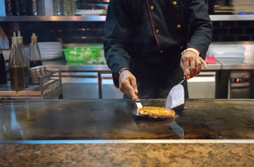 Hand of Chef cooking japanese patty on hot pan.