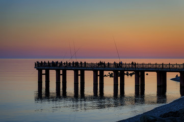 Obraz premium pier at sunset with fisherman