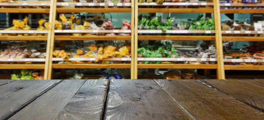 Department of baking in the supermarket. Shelves with fresh bread and sweets. Defocused, blurred image. In the foreground is the top of a wooden table, counter.