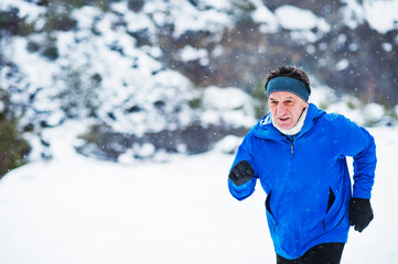 Fototapeta na wymiar Senior man jogging in winter nature. Copy space.