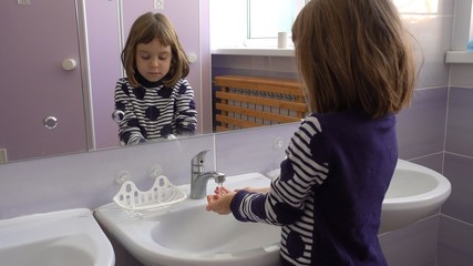 Kindergarten. Baby in the washroom. A girl 4-5 years washes her hands.