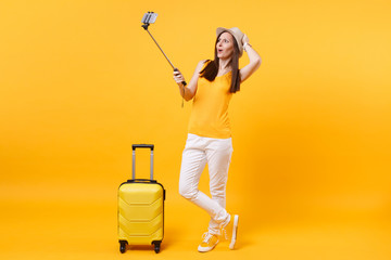 Happy tourist woman in summer casual clothes, hat doing selfie shot on mobile phone isolated on yellow orange background. Passenger traveling abroad to travel on weekends getaway. Air flight concept.