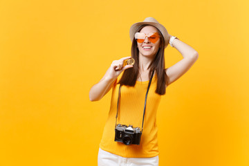 Tourist woman in summer casual clothes, hat holding bitcoin, metal coin of golden color isolated on yellow orange background. Female traveling abroad to travel on weekends getaway. Air flight concept.
