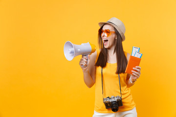 Expressive tourist woman in summer casual clothes hat holding megaphone passport tickets isolated on yellow orange background. Female traveling abroad to travel on weekends getaway. Air flight concept