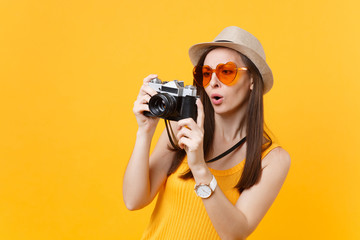 Tourist woman in summer casual clothes, hat take picture on retro vintage photo camera isolated on yellow background. Girl traveling abroad to travel on weekends getaway. Air flight journey concept.