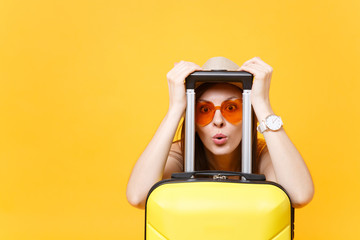 Fun traveler tourist woman in summer casual clothes hat look through suitcase isolated on yellow orange background. Passenger traveling abroad to travel on weekends getaway. Air flight journey concept