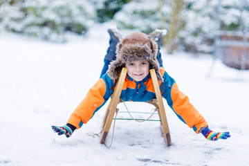 Little kid boy having fung with sleigh ride in winter
